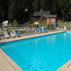 a large blue swimming pool with chairs and tables at Au bois de Calais in Corrèze