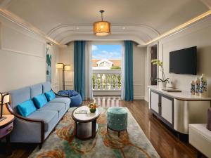 ein Wohnzimmer mit einem blauen Sofa und einem Fenster in der Unterkunft Hotel Royal Hoi An - MGallery in Hoi An