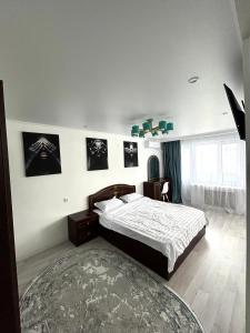 um quarto com uma cama e pinturas na parede em Уютная, светлая квартира-студия в районе Акмешит em Qyzylorda