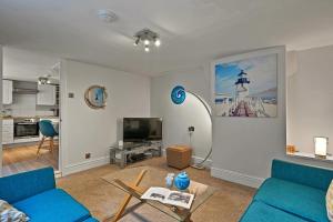 a living room with a blue couch and a tv at Finest Retreats - Porthole Cottage in Mevagissey