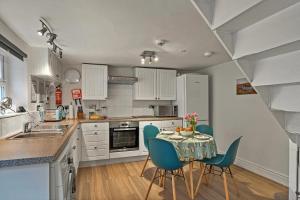 Finest Retreats - Porthole Cottage في ميفاغيسي: مطبخ مع طاولة وكراسي زرقاء في مطبخ