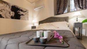 un vassoio con due tazze e fiori su un letto di Duomo Luxury Suite Catania a Catania
