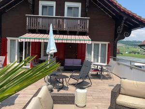 a patio with chairs and an umbrella on a house at Pension Chalet Charme in Siebnen