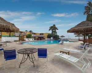una piscina con sillas, una mesa y una mesa con sillas en Quality Inn & Suites on the Beach, en Corpus Christi