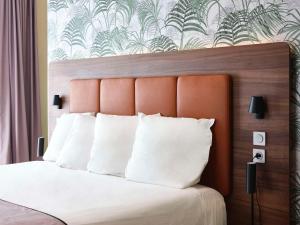 a bedroom with a white bed with an orange headboard at Quality Hotel Bordeaux Centre in Bordeaux