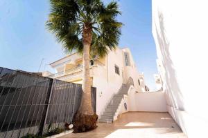 un palmier devant un bâtiment blanc dans l'établissement Adosado con vistas al Mar Menor y parking, à Santiago de la Ribera