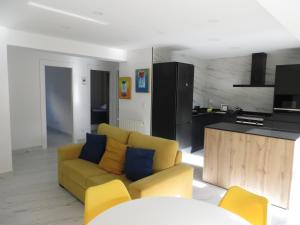 a living room with a yellow couch and a kitchen at Apartamento JARDIN DELUZ, con Wifi y Parking privado gratis in Santander