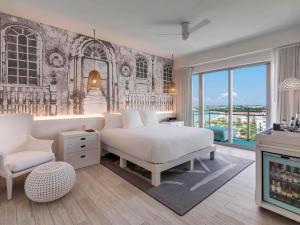 a bedroom with a white bed and a chair at SLS at Baha Mar in Nassau