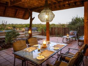 a dining table on a patio with a chandelier at Simbavati Mvubu Cottage in Timbavati Game Reserve