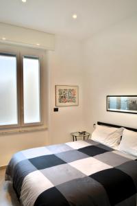 una camera con un letto bianco e nero e due finestre di Piazza Della Vittoria Apartment a Genova