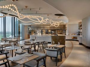 a restaurant with tables and chairs and a bar at Pullman Auckland Airport in Auckland