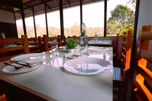 a table in a restaurant with white plates and glasses at Elenji Revive Resort in Munnar