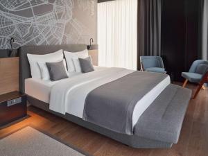 a bedroom with a large bed and two chairs at Mövenpick Zagreb in Zagreb