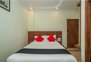a bedroom with a large bed with red pillows at HOTEL SAVI iNN in Bangalore