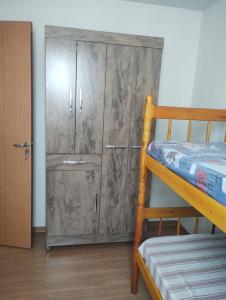 Cette chambre comprend une armoire en bois et des lits superposés. dans l'établissement Apartamento em Santa Barbara D'oeste, 