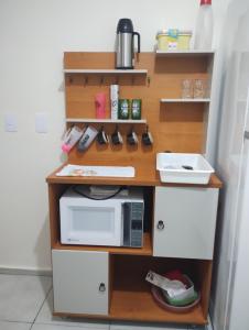 a book shelf with a microwave and a counter top at Apartamento em Santa Barbara D'oeste 