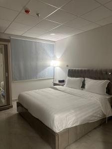 a large white bed in a room with a lamp at الساعه 60 للشقق المخدومه in Dammam +31 photos