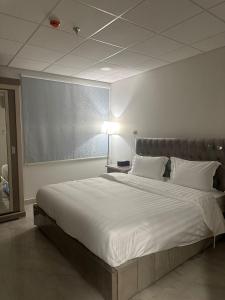 een groot wit bed in een kamer met een lamp bij الساعه 60 الفندقيه in Dammam