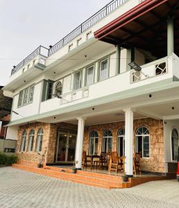 VIP Hotel And Villa في بيرووالا: مبنى به كراسي وطاولات على الشرفة
