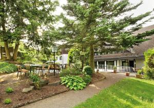 a garden with a table and chairs and trees at Landhotel Goldener Acker in Morsbach