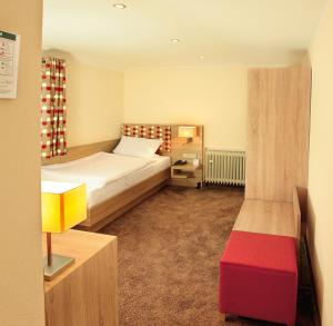1 dormitorio con cama y reposapiés rojo en Landhotel Goldener Acker en Morsbach