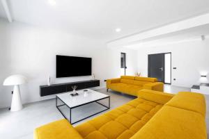 sala de estar con 2 sofás amarillos y TV en Hillside Rest, en Čelopeci