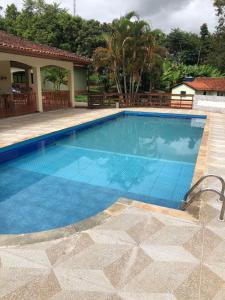 uma piscina com água azul em frente a uma casa em Sitio em Pinhalzinho