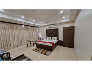 een slaapkamer met een bed, een tafel en een stoel bij Hotel Silver Arcade Premier, Malda, WB in Māldah