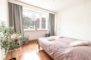 a bedroom with a bed and a large window at 2ndhomes Cozy 1BR Apartment w/ Balcony next to tram stop in Helsinki