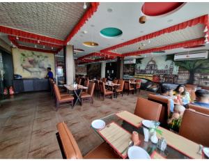 un ristorante con tavoli e sedie e persone sedute in esso di Hotel Silver Arcade Premier, Malda, WB a Māldah