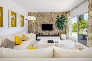 ein Wohnzimmer mit einem weißen Sofa und einem TV in der Unterkunft Charming Vale do Lobo Villa - 4 Bedrooms - Villa Quadradinhos 22 - Private Pool and Close to Amenities - Algarve in Almancil