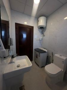 a bathroom with a white toilet and a sink at الساعه 60 الفندقيه in Dammam