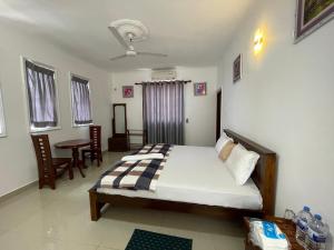 VIP Hotel And Villa في بيرووالا: غرفة نوم بسرير وطاولة وكراسي