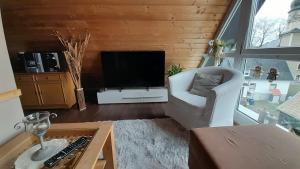 uma sala de estar com televisão e uma cadeira branca em Traumhaus em Werda