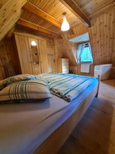 a large bed in a room with a wooden ceiling at Ferienhaus "BASTEK2" am See mit Kamin & WLAN - Domek Letniskowy BASTEK in Pasym