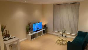 sala de estar con TV de pantalla plana y sofá en Free parking near city centre & stadium sleeps 6-8 en Leicester