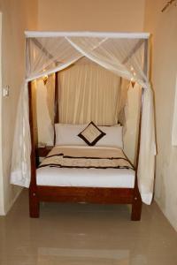 a bedroom with a canopy bed with white curtains at The Island Stone Town hotel in Ngambo