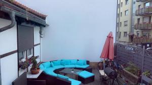 einen Balkon mit einem blauen Sofa, einem Tisch und einem Sonnenschirm in der Unterkunft Rubys1 in Frankfurt am Main