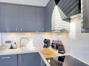 a kitchen with blue cabinets and a sink at Harrogate House Apt 4 - Cheltenham Parade Loft in Harrogate