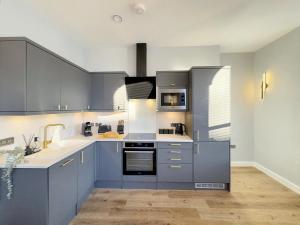 a kitchen with blue cabinets and a sink at Harrogate House Apt 4 - Cheltenham Parade Loft in Harrogate