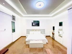 a white bedroom with a bed and a desk at Avrum Homes in Abuja