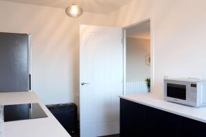 a kitchen with a counter with a microwave and a door at Seaside Apartment in Largs