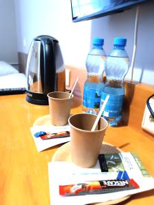 two cups on a table with two bottles of water at Hostel Krośnieńska 12 in Zielona Góra