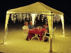 Rindali Maldives Maaenboodhoo في دالو أتول: مجموعة من الناس يجلسون على طاولة في خيمة على الشاطئ