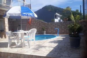 a table and chairs with an umbrella next to a pool at Studio pet friendly 03 in Matinhos