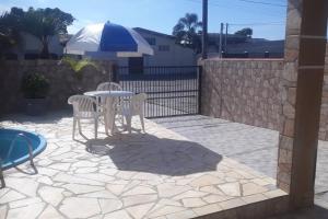 a patio with a table and chairs and a fence at Studio pet friendly 03 in Matinhos