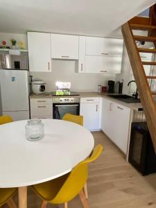 eine Küche mit einem weißen Tisch und gelben Stühlen in der Unterkunft Maison individuelle avec jardin ensoleillé in Auribeau-sur-Siagne