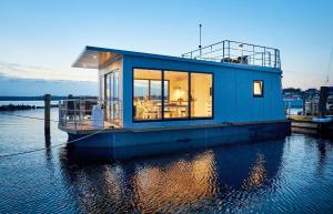 Egernsund的住宿－Hausboot WELL - Husbåd WELL，水面上的蓝色房子
