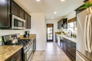 a kitchen with stainless steel appliances and brown cabinets at Spanish-Style Long Beach Bungalow Near Beaches! in Long Beach