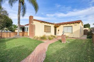 a house with a brick walkway in front of a yard at Spanish-Style Long Beach Bungalow Near Beaches! in Long Beach